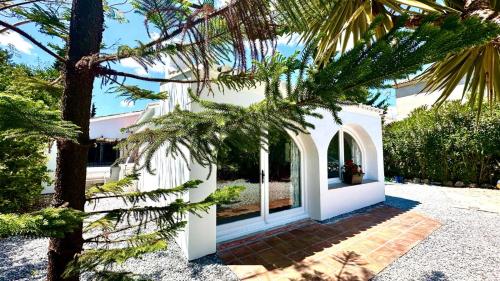 una casa blanca con árboles en primer plano en Villa vistas al lago with private pool, en Viñuela