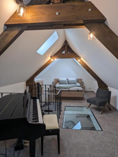 Cette chambre mansardée comprend un piano et un lit. dans l'établissement Grand appartement centre ville, à Bellême