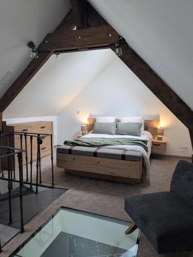 une chambre avec un lit et une chaise dans un grenier dans l'établissement Grand appartement centre ville, à Bellême