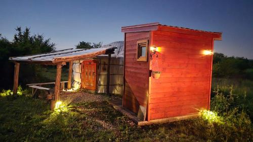 a small red shed with lights in the grass at DuVa mongolska yurta in Bistrica