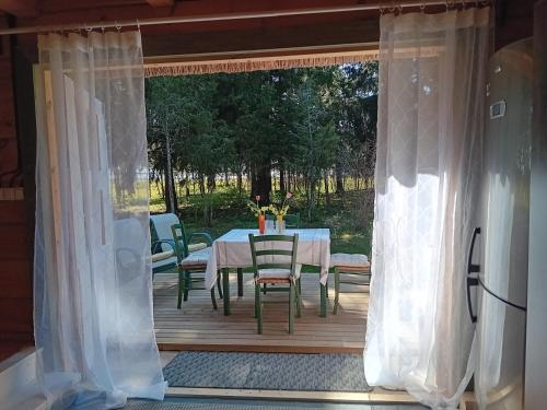 a table and chairs on a wooden deck with a window at Merevaatega puhkemaja Pädaste lahe ääres in Pädaste