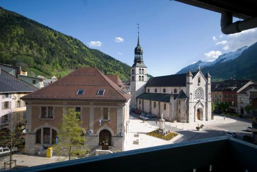 a view of a church and a building with a tower at Hôtel Du Midi in Thônes