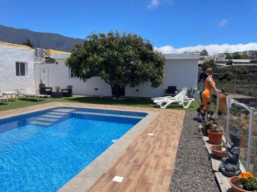 zwei Personen stehen neben einem Pool in der Unterkunft Casa Mango, con piscina y vistas al mar y volcán in El Paso