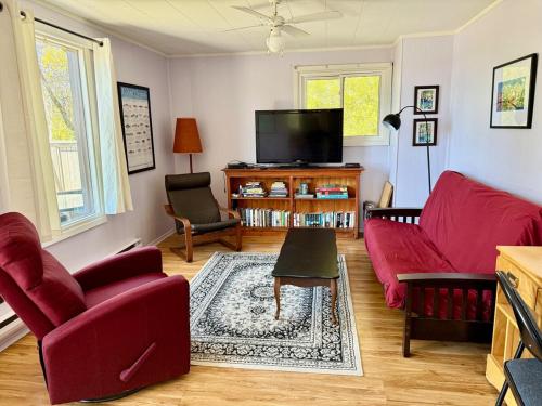 a living room with red furniture and a flat screen tv at All Star Inn cottage on water with stunning sunsets in Tobermory