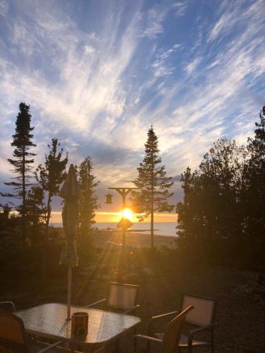 a table and chairs with the sunset in the background at All Star Inn cottage on water with stunning sunsets in Tobermory