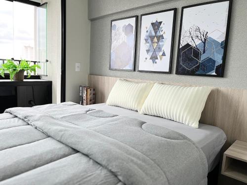 1 dormitorio con 1 cama con 4 cuadros en la pared en Sweet Home Alto Boa Vista, en São Paulo