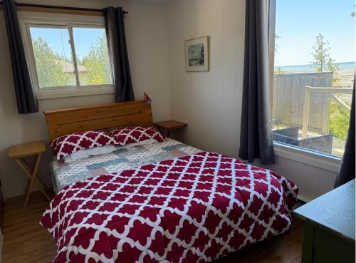 a bedroom with a red and white bed and a window at All Star Inn cottage on water with stunning sunsets in Tobermory