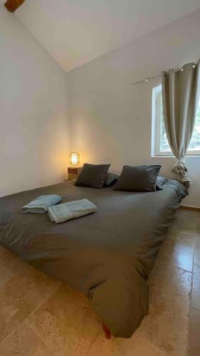 un grand lit dans une chambre avec une fenêtre dans l'établissement Maison au pied du Luberon avec Piscine Privée et Terrain de Boules, à Lourmarin