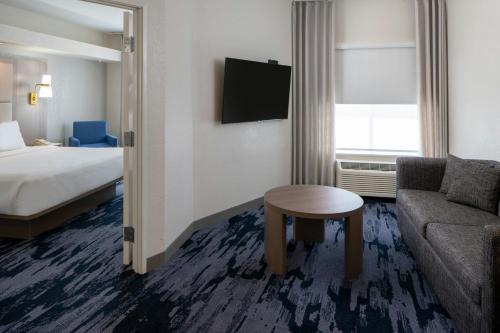 a hotel room with a bed and a couch and a table at Fairfield Inn & Suites by Marriott Lafayette South in Lafayette