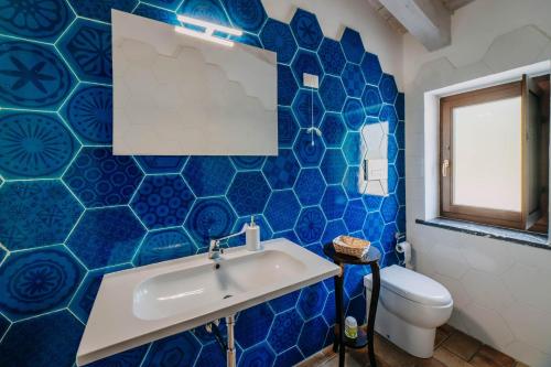 a blue tiled bathroom with a sink and a toilet at Tenuta Le Tre Rose in Vibonati