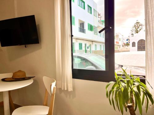 a room with a window with a table and a plant at Weybeach2 -shared terrace,plaza view,sea frontline in La Santa