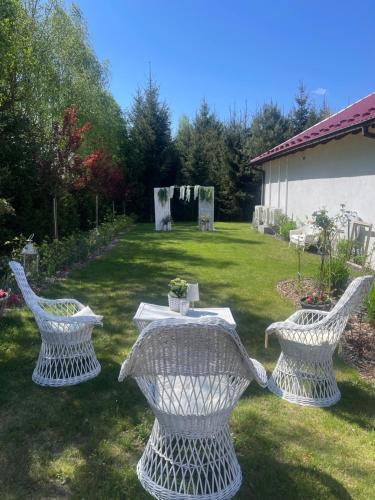 two white chairs and a table in a yard at Agro na Wapniarni in Białla