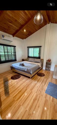a bedroom with a bed and a wooden floor at Noi’s Paradise Homestay in Phatthalung