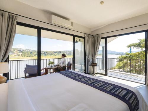 una camera con un grande letto e un balcone di Fortune Riverview Hotel Chiang Khong a Chiang Khong