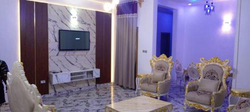 a living room with two chairs and a tv at good shepherd apartment in Owerri