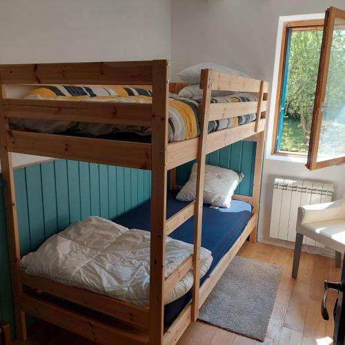two bunk beds in a room with a window at Maison au calme avec jardin exotique pour 7 personnes in Thorigné-sur-Dué