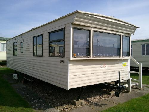 a white tiny house sitting in a yard at Promenade Resort 6 Berth Access to the beach in Ingoldmells
