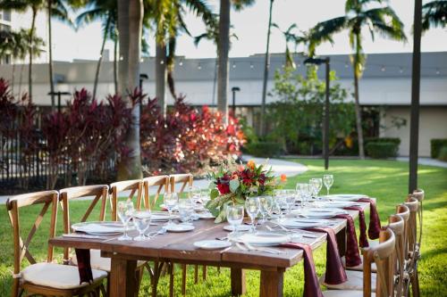 a long wooden table with glasses and flowers on it at Miami Airport Marriott in Miami