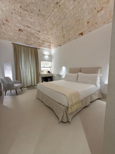 a white bedroom with a large bed and a chair at La Volta in Locorotondo