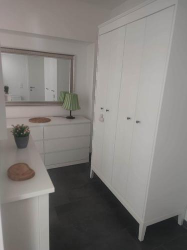a white kitchen with white cabinets and a table at Wohnen bei frau tinz - Studio - Bahnhof- und Zentrumsnähe in Neunkirchen