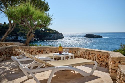 a table and chairs on a patio with the ocean at Sea frontline Apartment 'Faraona'. Pool. WIFI in Santanyi