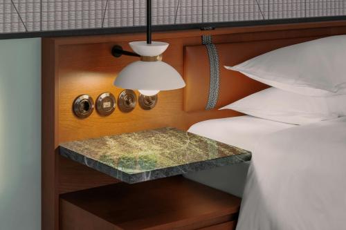 a bed with a night stand next to a bed with a lamp at Sheraton Stockholm Hotel in Stockholm