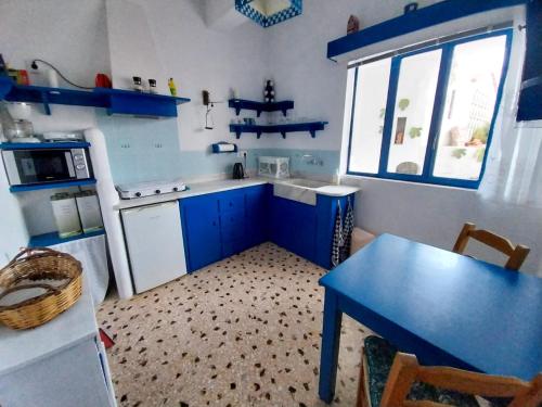 a small kitchen with blue cabinets and a blue table at Blue on The Beach in Poros