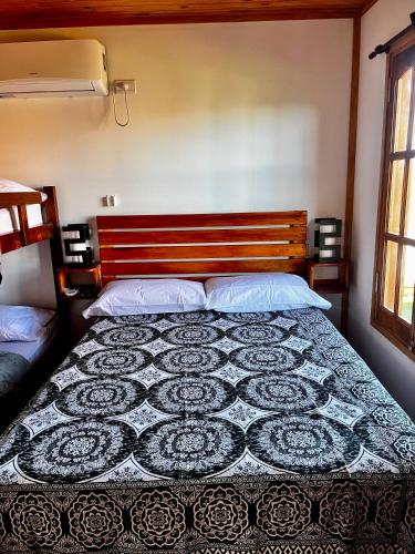 a bedroom with a bed with a black and white quilt at Complejo de cabañas Tikuna in Concepción del Uruguay