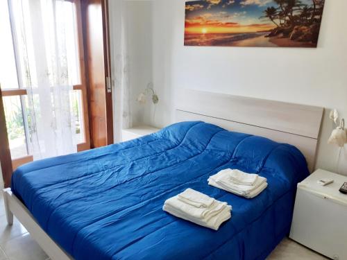 a bedroom with a blue bed with towels on it at B&B il boschetto in Ogliastro Cilento