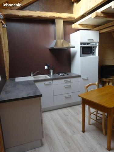 Il comprend une cuisine équipée d'un évier, d'une cuisinière et d'une table. dans l'établissement Gite 2-3 personnes Arçon proche Pontarlier, à Arçon