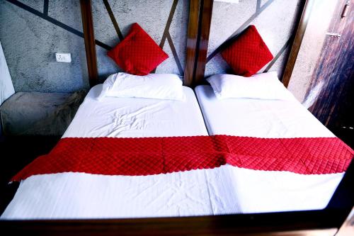 two beds with red and white sheets and pillows at The Escape Resort in Mussoorie