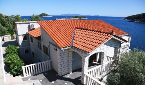 BlatoにあるApartmani Bošković - otok Korčulaの水辺に建つオレンジ色の屋根の家