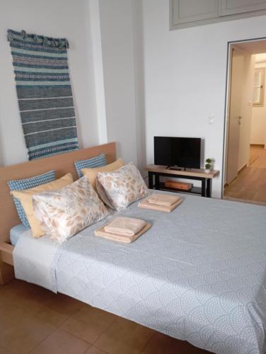 a bedroom with a bed with pillows and a television at Aegina Port Apt 4 in Egina