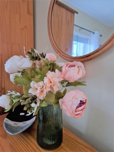 a vase with pink flowers on a table in front of a mirror at No1 Harbour view apartment Killybegs in Killybegs