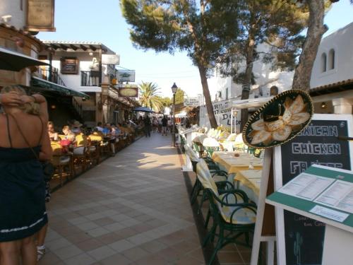 a group of people sitting at tables on a street at Sea frontline Apartment 'Faraona'. Pool. WIFI in Santanyi
