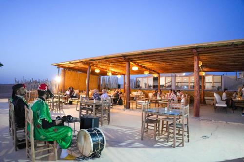 two people sitting in chairs in front of a restaurant at Kal Tenere Agafay Luxury Camp in El Karia