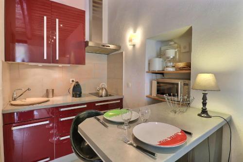 une cuisine avec des placards rouges et une table avec des verres à vin dans l'établissement The Cassidaine getaway hyper center studio, à Cassis