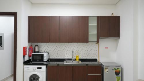 a kitchen with wooden cabinets and a sink and a microwave at Golden Homes 2 in Dubai