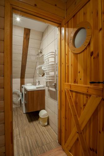 a bathroom with a toilet and a sink and a wooden door at Ziaciówka Noclegi Premium w Górach in Rzepiska