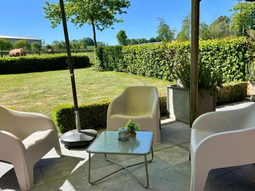 a patio with white chairs and a table at Au Coeur des Collines, Gloriette in Ellezelles