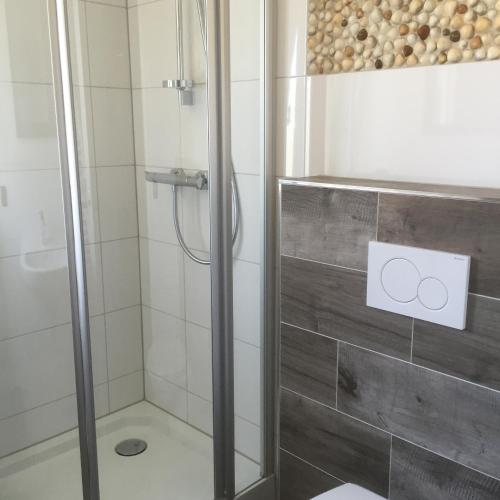 a shower with a glass door in a bathroom at Bed & Breakfast Zeeland in Renesse