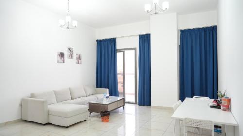 a living room with a white couch and blue curtains at Golden Homes 2 in Dubai