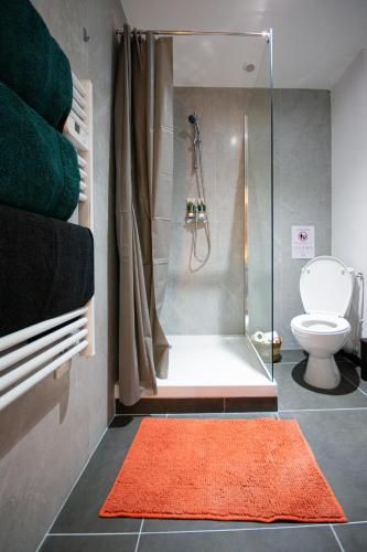 une salle de bain avec une douche avec des toilettes et un tapis orange dans l'établissement Le Terracotta, plein centre, garage, WIFI-Netflix, à Montbéliard