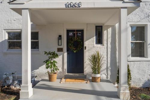 a white house with a blue door with two potted plants at Cozy 3 Bedroom Home in Historic Kennett Square in Kennett Square