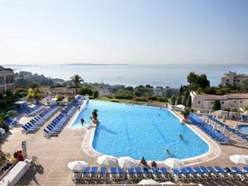 une grande piscine avec des chaises et des parasols bleus dans l'établissement Charmant appartement dans résidence avec piscine vue mer, à Cannes