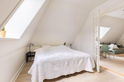 a white bedroom with a bed and a chair at 2 værelses lejlighed i hjertet af Odense tæt på alt in Odense