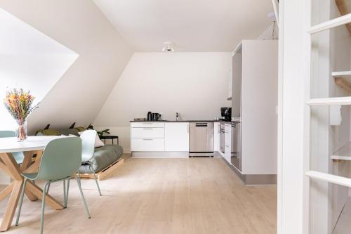 a kitchen and dining room with white cabinets and a table and chairs at 2 værelses lejlighed i hjertet af Odense tæt på alt in Odense