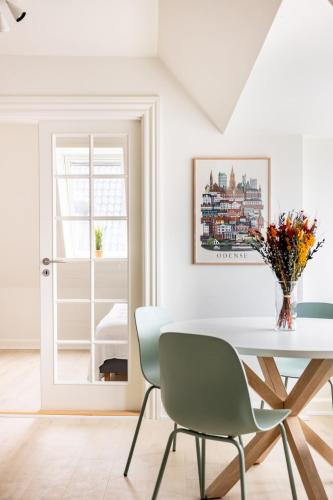 a white dining room with a table and chairs at 2 værelses lejlighed i hjertet af Odense tæt på alt in Odense