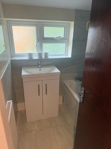 a bathroom with a sink and a bath tub at D'Luxe Royal 3 bedrooms house in Abbeywood, London in Belvedere
