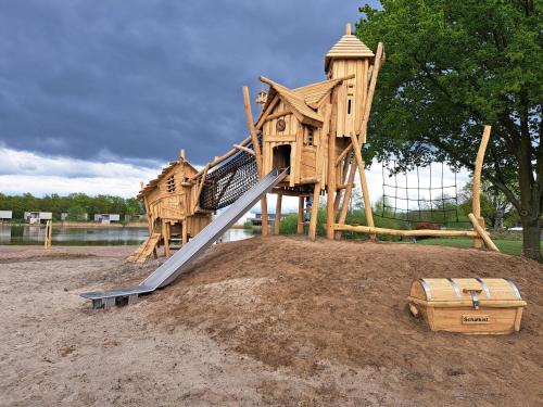 a wooden playground with a slide in the sand at Boshuisje op de Schatberg in Sevenum